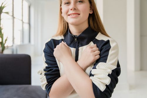 Free Casual portrait of a smiling woman with crossed arms in a modern indoor setting. Stock Photo