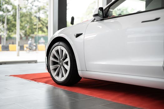 Sleek white electric car on display in a modern showroom on a red carpet.