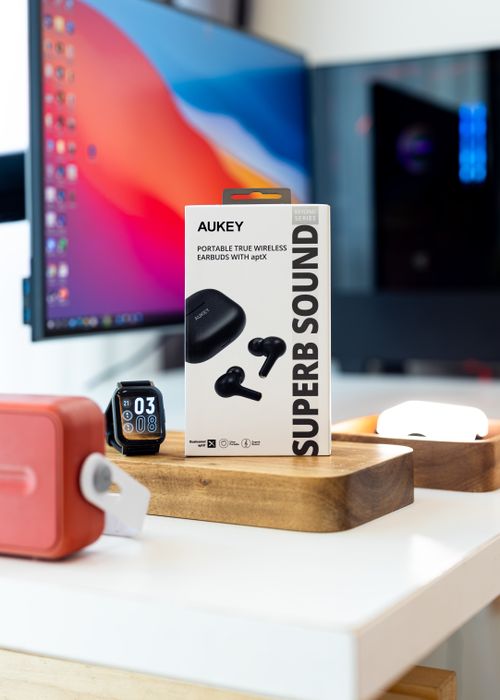Free AUKEY wireless earbuds and smart watch showcased on a modern desk setup. Stock Photo