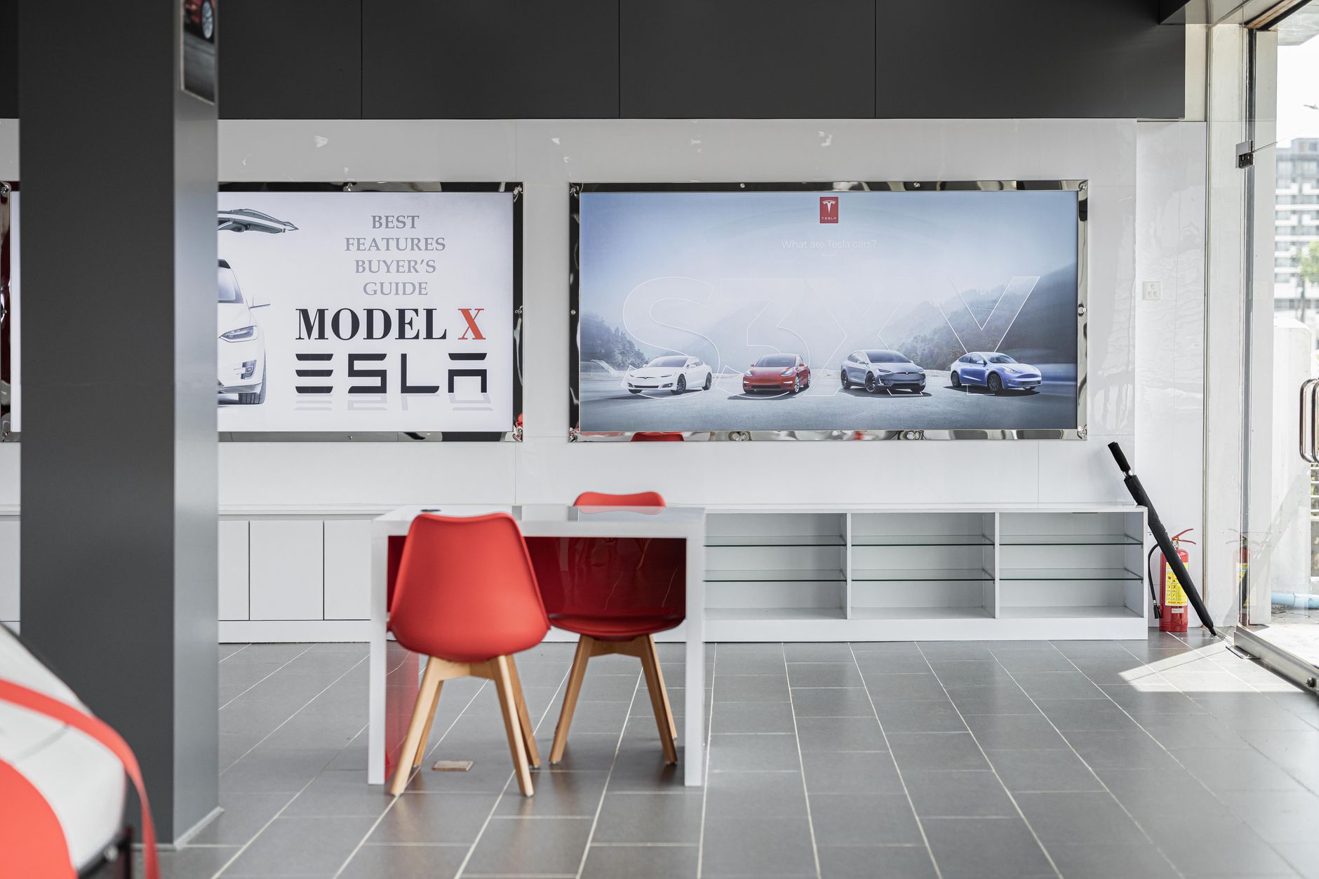Spacious car dealership interior featuring red chairs and advertising displays with electric cars.