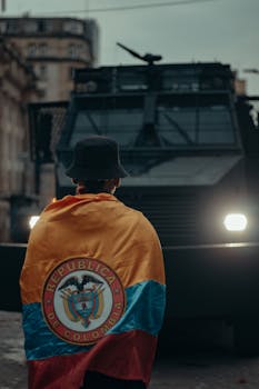 A person wrapped in Colombia's flag stands in front of an armored vehicle during a protest in Bogotá.