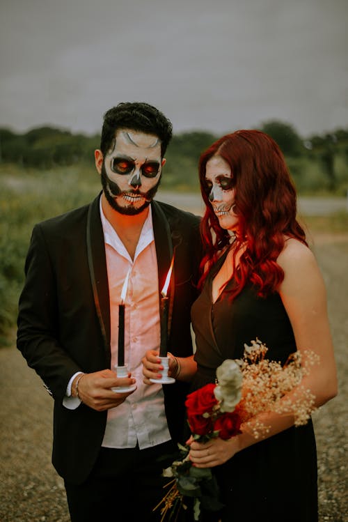 Man and Woman with Face Paint Holding Lighted Candles