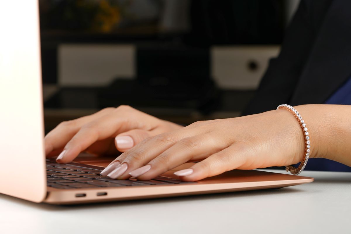 Person wearing a diamond bracelet while typing at a laptop