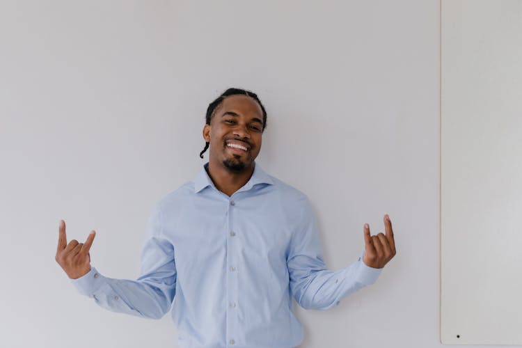 Portrait Of Smiling Man Showing Horn Sign