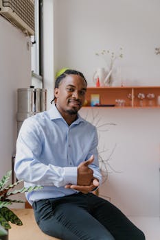 Businessman with hearing aid using sign language in a modern office space, promoting individuality and communication.