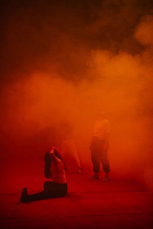 Free Atmospheric scene with people in artistic performance surrounded by smoke and orange lighting. Stock Photo