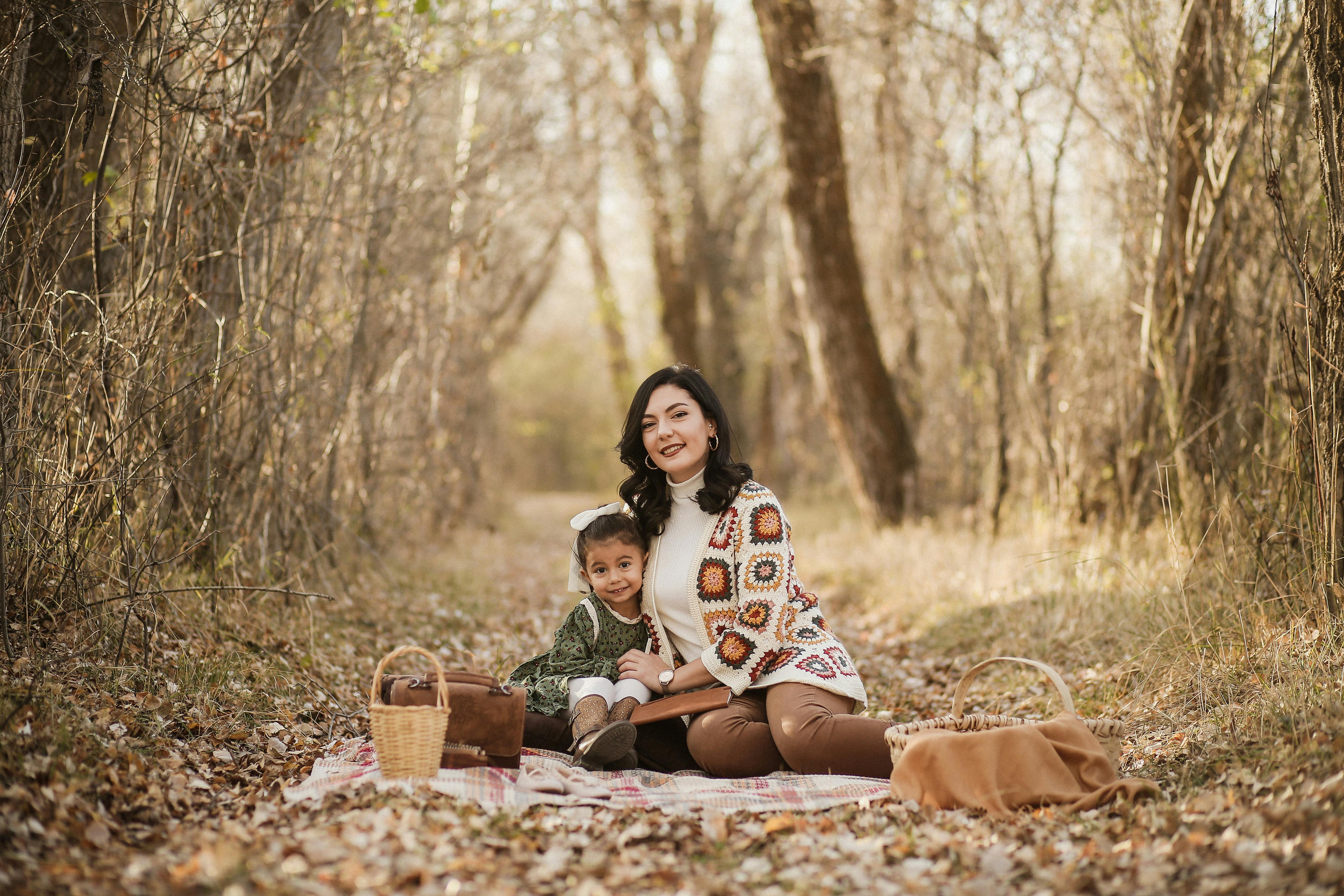 Mother and daughter enjoying an autumn picnic in a serene forest setting.
