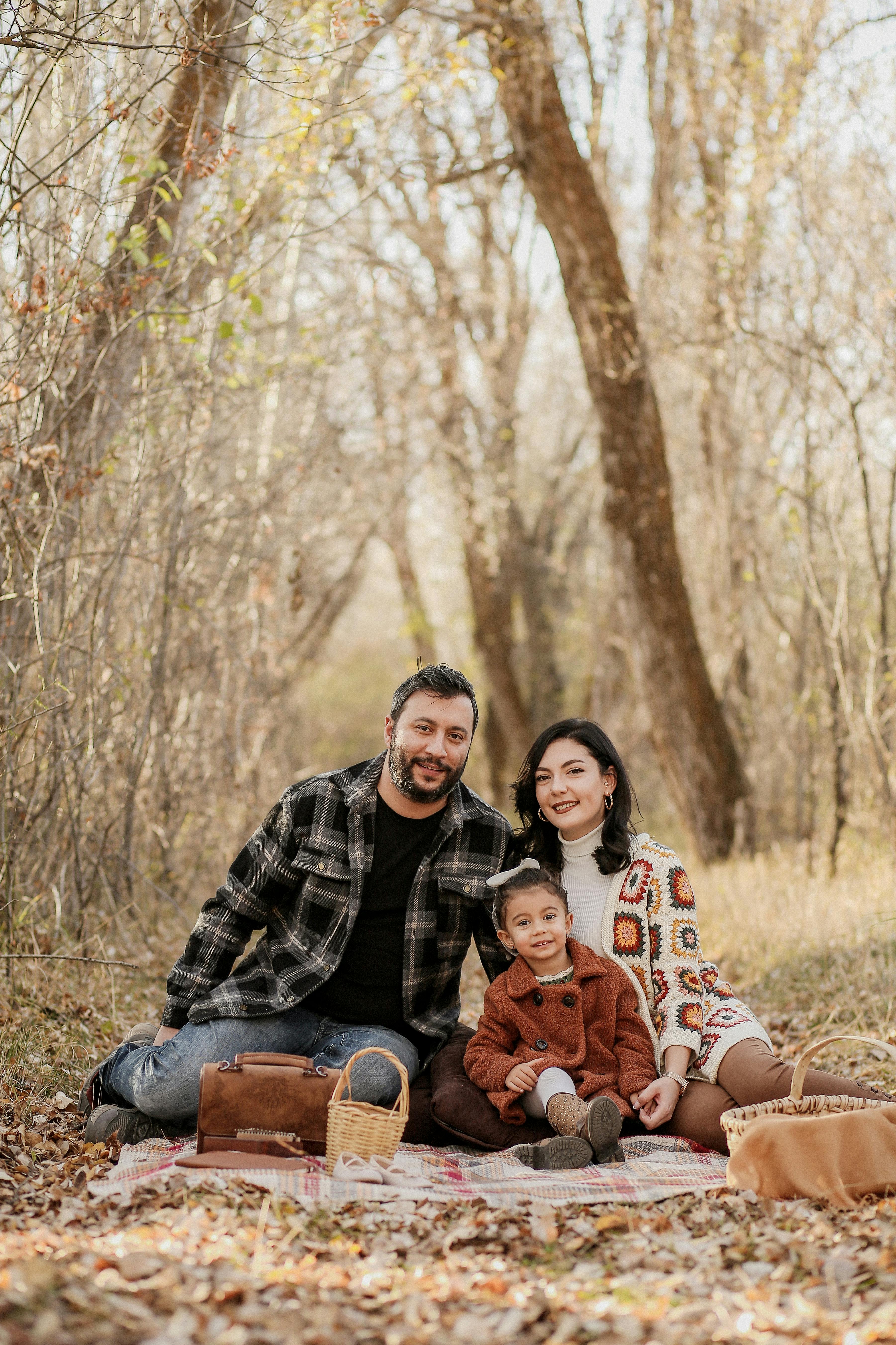 A cheerful family of three enjoying a cozy autumn picnic in a serene forest setting.