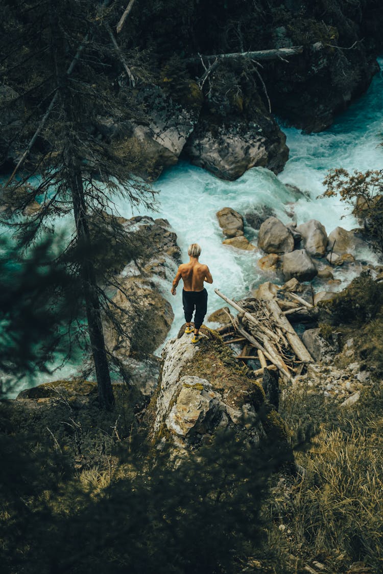 A High Angle View Of Shirtless Male Standing In Front Of Torrent 