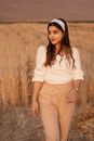 Woman in White Long Sleeve Shirt and Brown Pants Standing on Brown Grass Field