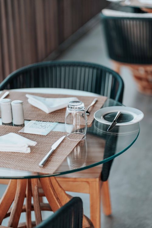 Free Glass-top table with cutlery and napkins at an elegant restaurant setting. Ideal stock for hospitality themes. Stock Photo