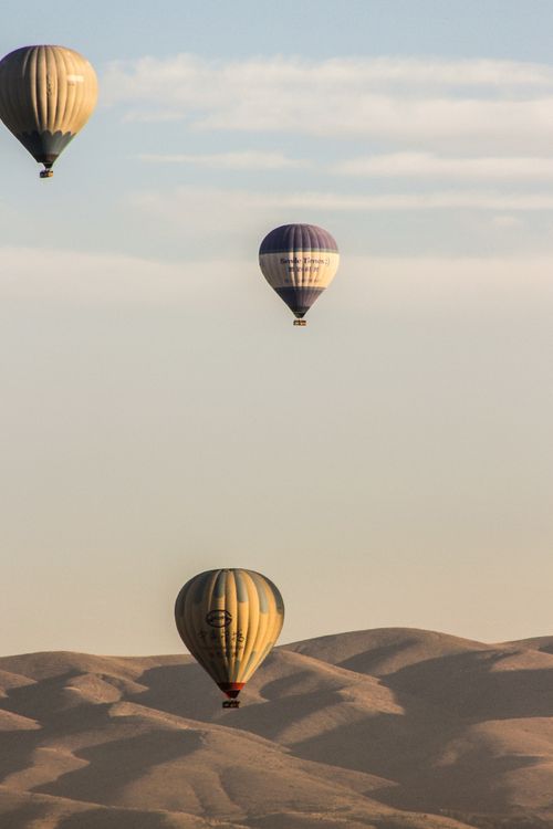 Free Hot air balloons floating over a serene desert landscape during the day. Stock Photo