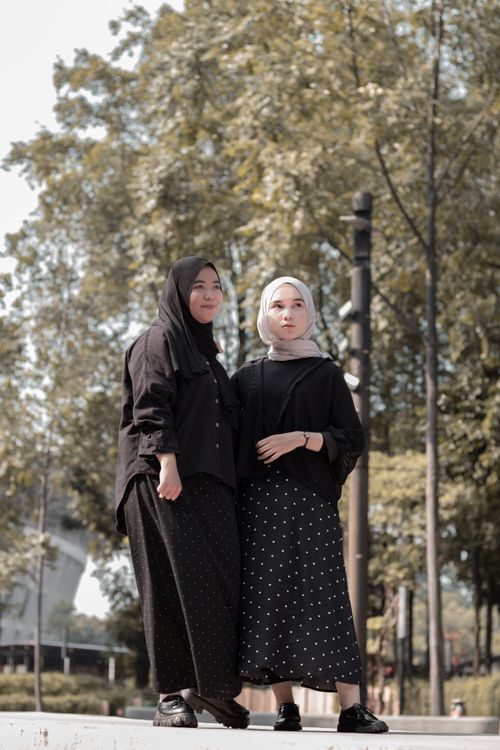 Free Two young women in hijabs posing outdoors, surrounded by trees. Stock Photo