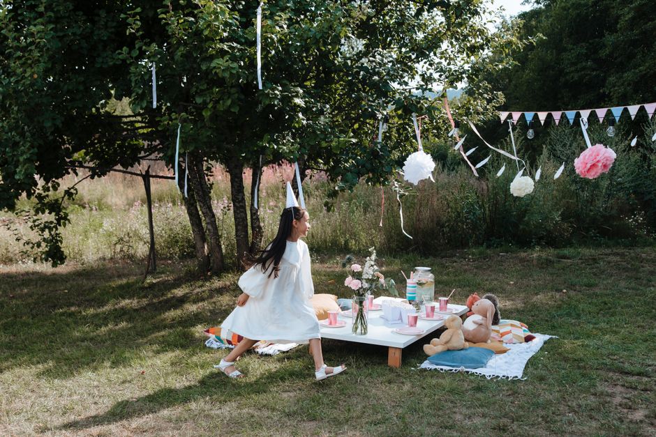 A whimsical garden party setup with a young girl playing outdoors surrounded by decorations.