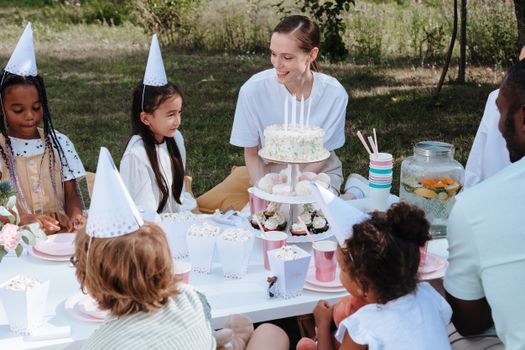 Children enjoying a lively outdoor birthday party with cake and decorations.
