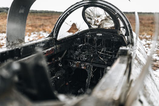 A close-up view of a destroyed cockpit in an abandoned aircraft wreckage in a snowy field.