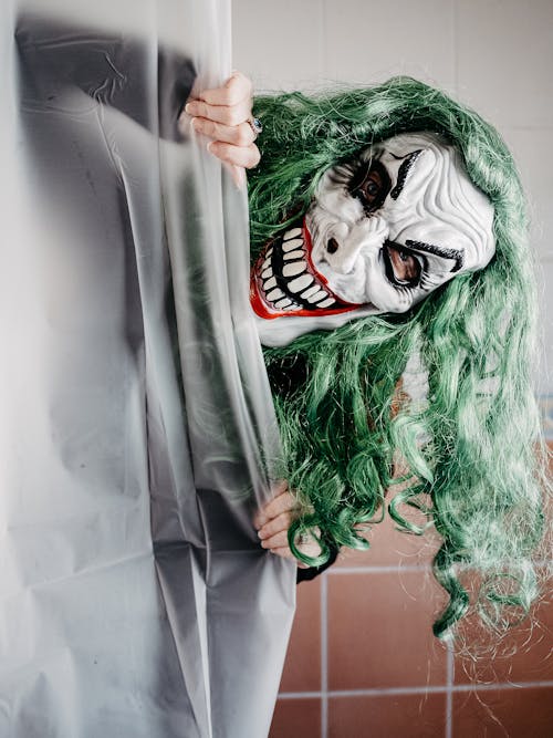 Person in Mask of Spooky Creature Looking From Behind Shower Curtain