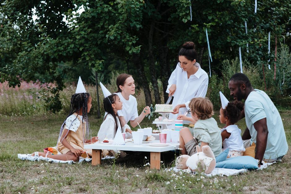 Multiracial family's outdoor birthday party. Joyful gathering in a garden setting.