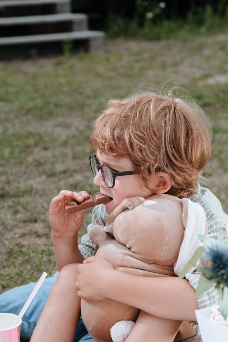 Boy Hugging Stuffed Toy And Eating Chocolate 