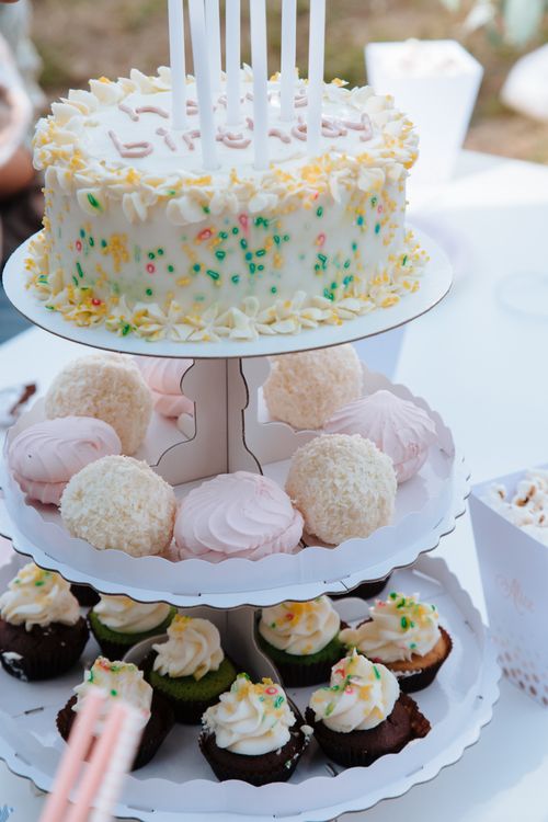 Free Festive display of birthday cake and cupcakes with sprinkles on a tiered stand, perfect for celebrations. Stock Photo