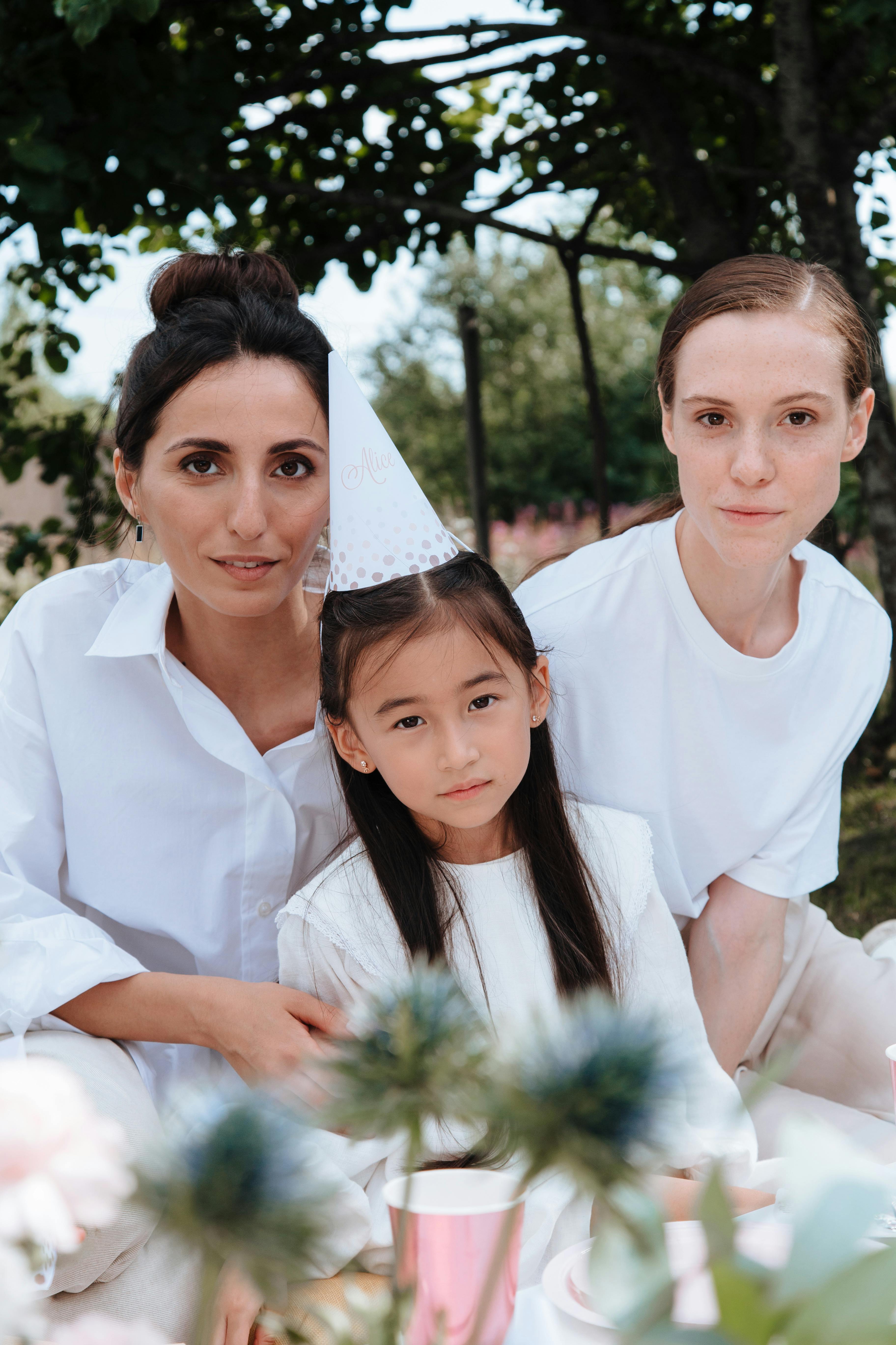 portrait of two women and girl in party hat in garden