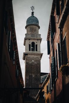 Low angle view of a historic church bell tower surrounded by colorful buildings.