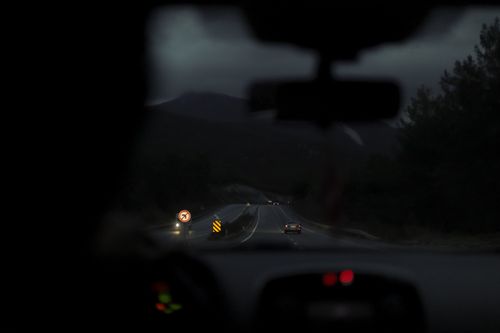Free Blurred view of a highway at night from inside a moving car, with headlights illuminating the road. Stock Photo
