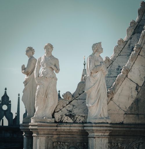 Free A captivating view of vintage sculptures on a historic rooftop under a clear blue sky. Stock Photo