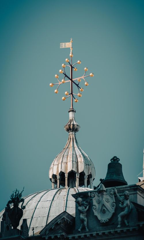 Free Detailed view of an intricate weather vane atop a dome with sculptures. Stock Photo