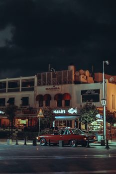 Classic vintage car parked on a dimly lit city street at night.