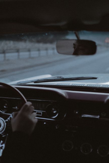 Driver navigating a classic car on a tranquil road, capturing nostalgia and adventure.