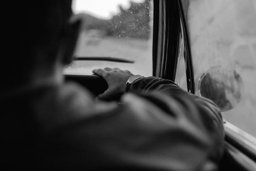 Moody black and white image capturing a passenger's perspective from inside a vehicle.