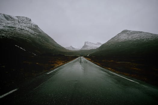 Moody scene of a wet road surrounded by rugged mountains in Norway.