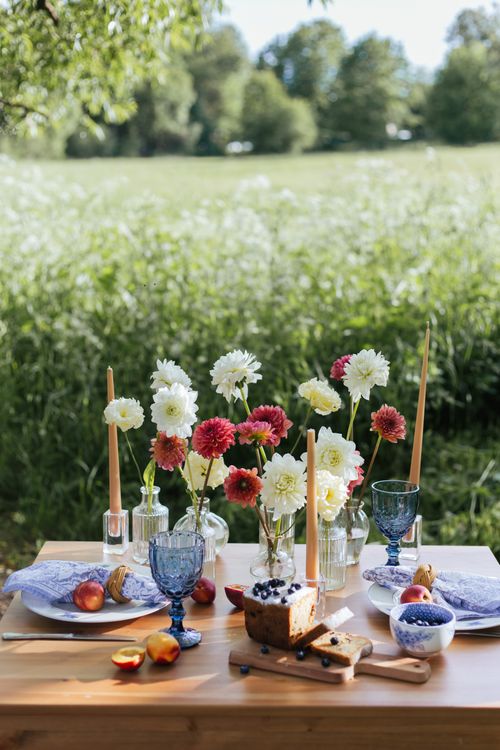 Free A beautifully arranged summer picnic table outdoors with flowers and fruits. Stock Photo