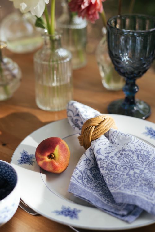 Free A close-up of a summer table setting featuring a peach and decorative napkin on fine china. Stock Photo