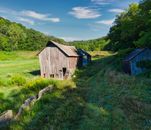 Brown Wooden House on Green Grass Field Under Blue Sky