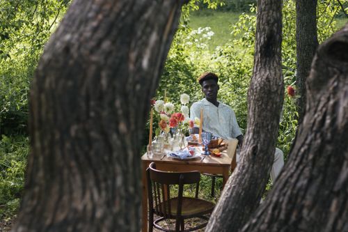 Free Black man sitting at a decorated table in a lush forest setting. Stock Photo