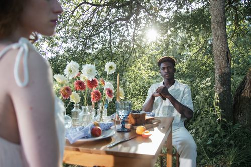 Free A couple enjoys a romantic outdoor dining experience surrounded by nature. Stock Photo