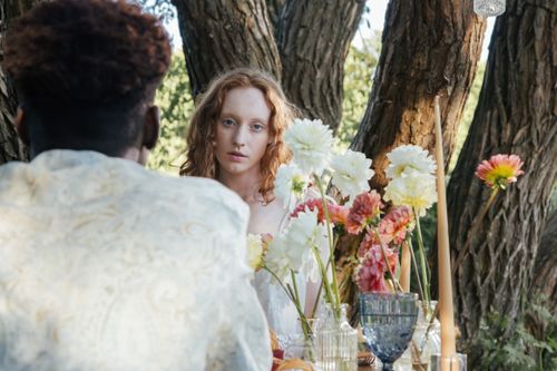 Free Young couple enjoying a romantic outdoor summer picnic surrounded by flowers. Stock Photo