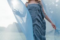 A Woman in Blue Dress Touching a Blue Sheer Fabric