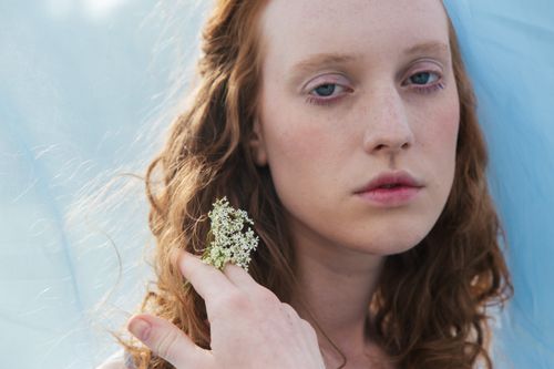 Free Intimate close-up of a woman holding white flowers, creating a serene mood. Stock Photo