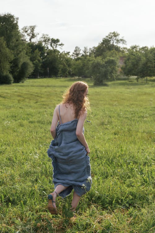 Woman in Blue Dress Running on Grass