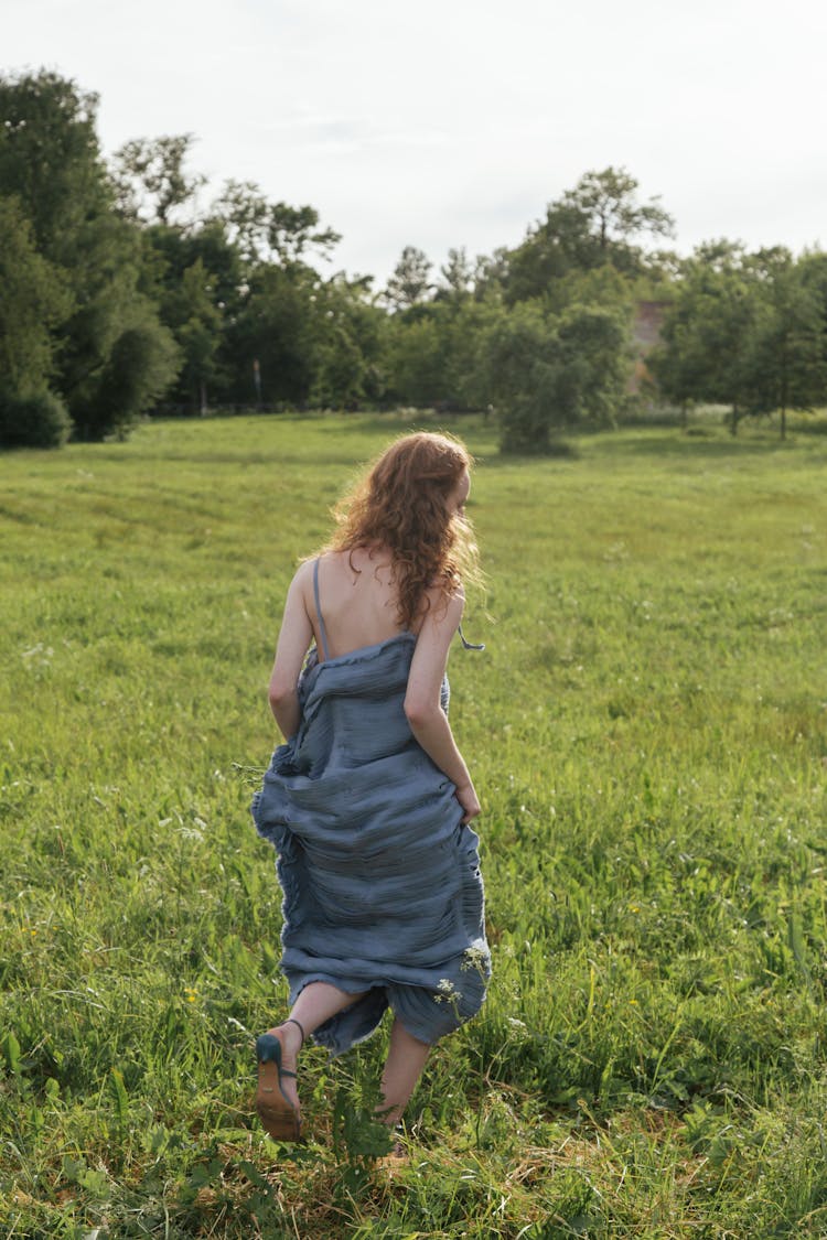 Woman In Blue Dress Running On Grass