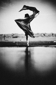 A graceful dancer captured in monochrome, wrapped in free-flowing fabric against a serene outdoor setting.