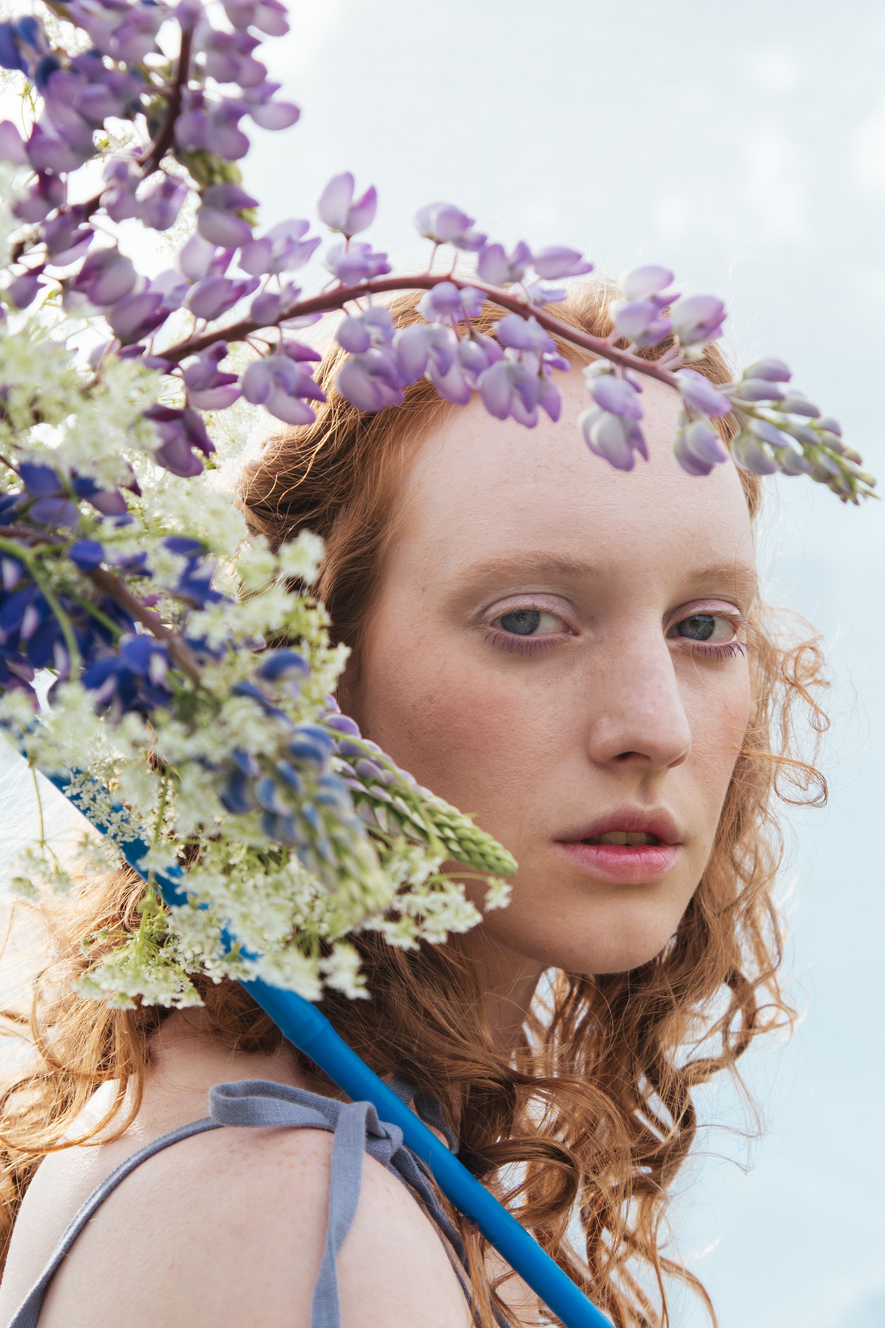 Elegant portrait of a red-haired woman adorned with purple and white flowers.