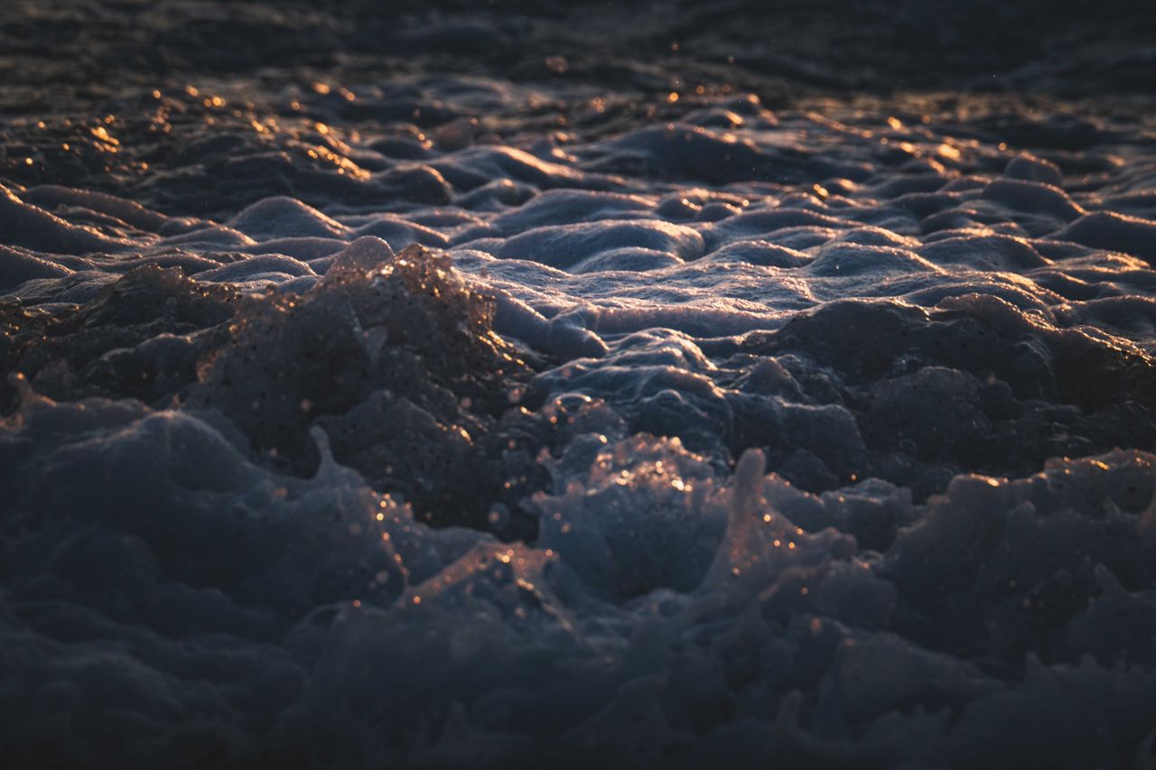 close up of ocean waves with sunlit foam during golden hour showcasing