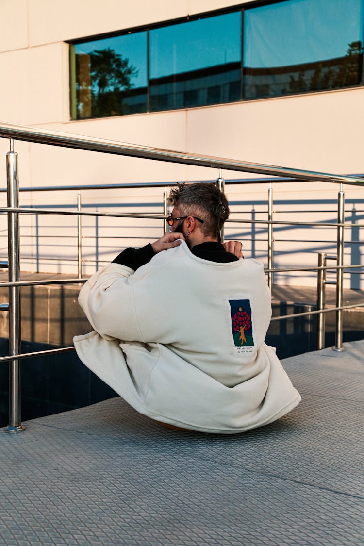 Man Putting On Coat While Sitting On Ground