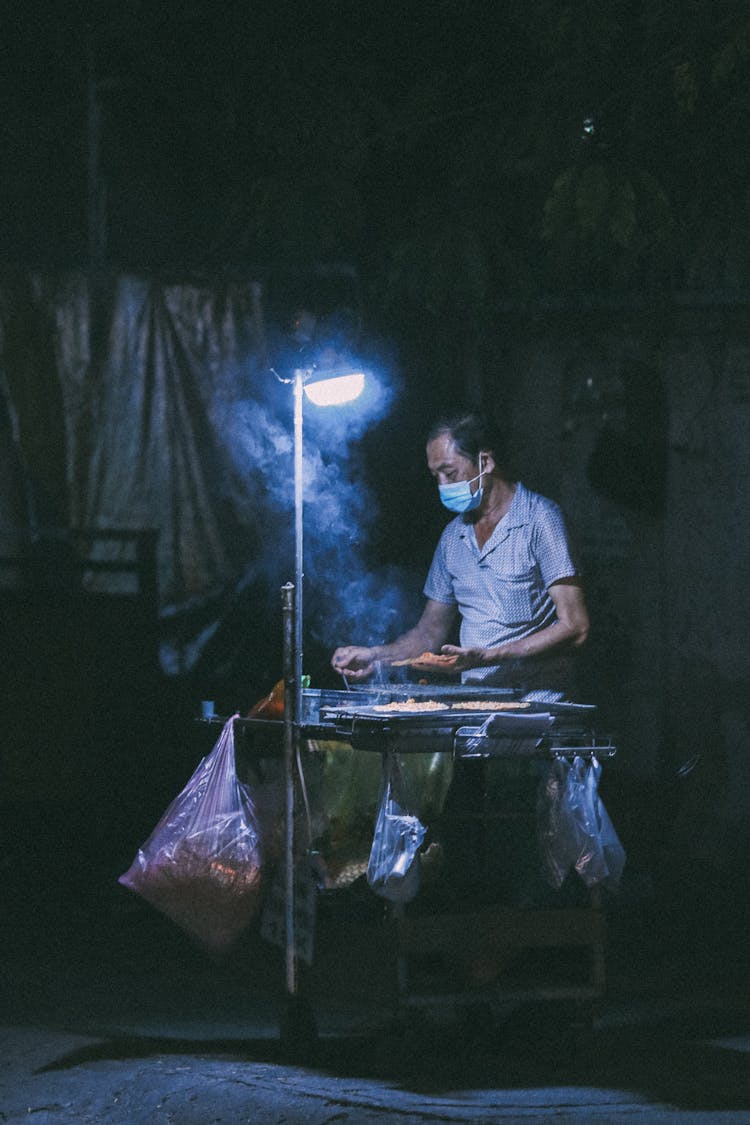 Street Vendor Selling From Stand At Night