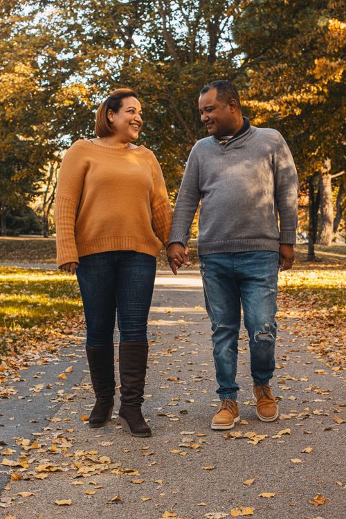 Free Smiling couple walking hand-in-hand on a leafy autumn path. Stock Photo