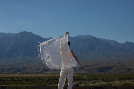 Person poses with sheer fabric in a mountain setting, conveying freedom and serenity.